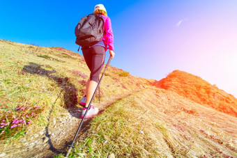 纤细的女人练习北欧走的山独自一人