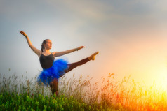 通美丽的芭蕾舞女演员跳舞在户外华丽的草地日落