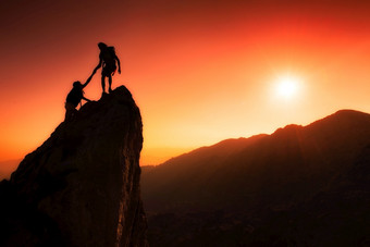 团队登山者帮助征服的峰会团队合作神奇的山景观日落