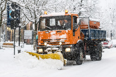 雪犁工作在降雪白色街道的城市