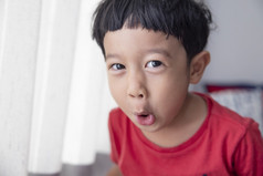 特写镜头肖像亚洲孩子男孩直黑色的头发穿红色的衬衫看相机他使有趣的脸快乐微笑广告儿童产品