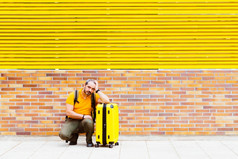 男人。橙色衬衫等待的地板上的街与手提箱男人。橙色衬衫等待的地板上的街与手提箱