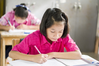 女亚洲学生的粉红色的统一的女学生坐考试的教室的教室农村学校泰国