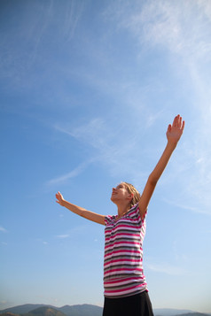 十几岁的女孩住与提高了手对蓝色的天空