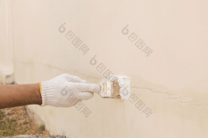 关闭手与白色布手套那被使用变换油漆密封的裂缝的混凝土墙