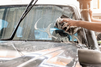 的车洗工作人员使用海绵清洁的挡风玻璃的车