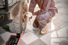 车修复工人穿黑暗蓝色的制服是使用工具删除的轮坚果检查和修复的车修复中心