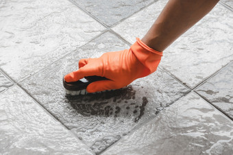 手男人。穿橙色橡胶手套使用转换擦洗清洁的瓷砖地板上