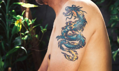 特写镜头美丽的彩色的龙纹身的左上手臂男人。