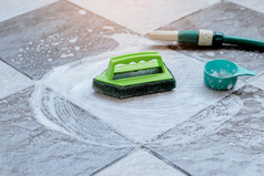 关闭的绿色塑料刷为擦洗和清洁的地板上放置的湿瓷砖地板上和泡沫与洗涤剂