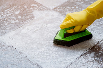 人类手穿黄色的橡胶<strong>手套</strong>是使用绿色颜色塑料地板上洗涤器擦洗的瓷砖地板上与地板上更清洁的