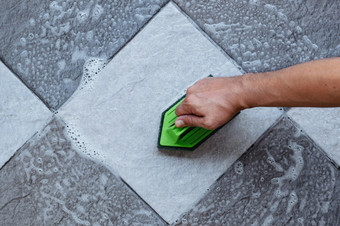 前视图人类手是使用绿色颜色塑料地板上洗涤器擦洗的瓷砖地板上与地板上更清洁的