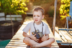 小男孩看通过双筒望远镜坐着的码头光着脚河银行