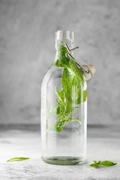 摇摆不定的前玻璃瓶与冷水与新鲜的薄荷叶子灰色混凝土背景食物摄影