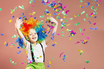 小男孩小丑假发跳和有有趣的庆祝生日肖像孩子抛出多色的俗丽的和五彩纸屑生日男孩积极的情绪