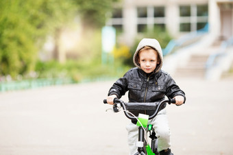 肖像可爱的小城市男孩穿黑色的<strong>皮革夹克</strong>城市风格城市孩子们的男孩学习骑自行车孩子开车自行车