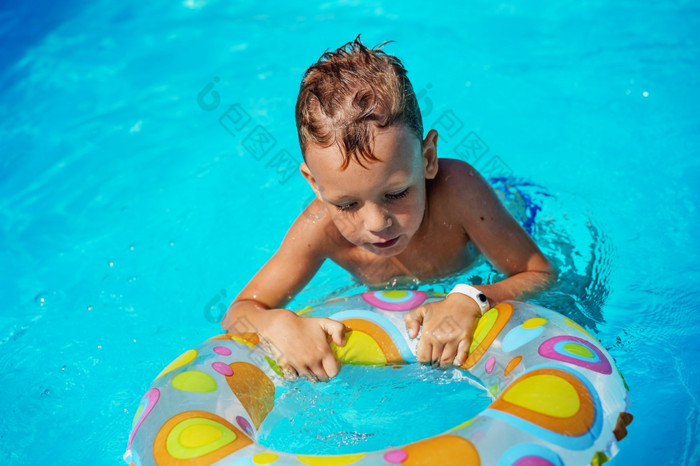 快乐孩子玩蓝色的水游泳池小男孩学习游泳与游泳环夏天假期概念可爱的男孩游泳池水孩子溅和有有趣的游泳池