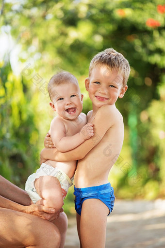 小孩子们玩在户外热夏天一天小男孩持有手她的婴儿妹妹