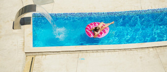快乐孩子玩蓝色的水游泳池热带度假胜地的海夏天假期概念可爱的女孩游泳池水孩子与游泳设备充气游泳圆