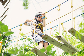 孩子们攀爬冒险公园男孩享受攀爬的绳子课程冒险孩子攀爬高线公园快乐男孩玩冒险公园持有绳子和攀爬木楼梯