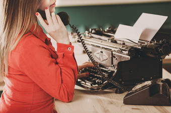 秘书老打字机与电话年轻的女人使用打字机业务概念复古的图片风格