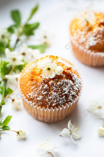 甜蜜的松饼与粉糖和花朵自制的面包店松饼白色胶囊装饰与水果树花春天时间面包店