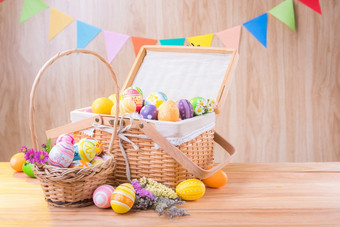 快乐复活节一天色彩斑斓的鸡蛋和花的篮子木地板上有模糊庆祝横幅聚会，派对旗帜与复制空间