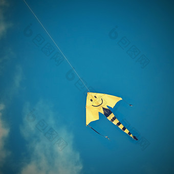 风筝飞行的美丽的秋天多风的一天蓝色的天空背景与太阳和云