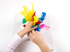 小女孩手玩与色彩斑斓的羽毛创建复活节装饰