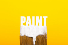 画笔与白色油漆在黄色的背景修复和绘画工具概念