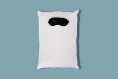 personofied白色绗缝枕头与睡觉面具蓝色的背景软缓冲为舒适的睡眠和甜蜜的做梦