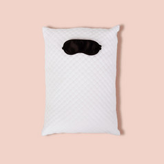 personofied白色绗缝枕头与睡觉面具粉红色的背景软缓冲为舒适的睡眠和甜蜜的做梦