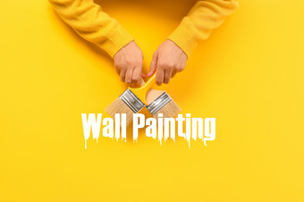 油漆刷手在黄色的背景墙绘画概念