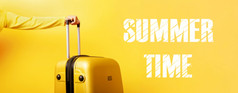 女人持有黄色的手提箱手和登记夏天时间在黄色的背景旅行概念全景图像