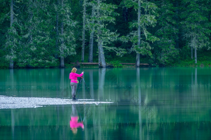 德国平静森林湖密集的森林女孩摄影师站的边缘的水和使照片与三脚架女孩摄影师的森林湖