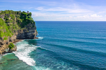 印尼高和岩石海岸的海洋一天小传统的寺庙前悬崖寺庙的沿海岩石