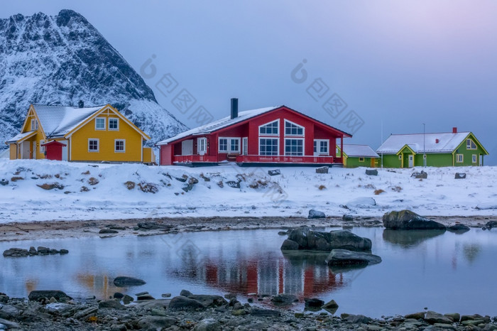 挪威多色的别墅的背景的山的海岸的峡湾冬天晚上低潮的峡湾和挪威别墅的冬天晚上