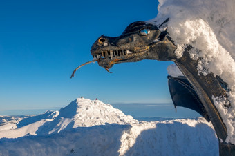 斯洛伐克滑雪度假胜地明亮阳光明媚的一天雕塑龙和很多雪的前山chopok白雪覆盖的山山峰的背景龙雕塑的前chopok山