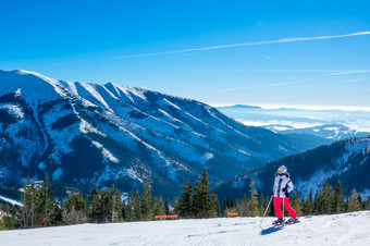 全景雪山冬天阳光明媚的一天女孩滑雪停止和欣赏的视图女孩滑雪欣赏的全景白雪覆盖的山
