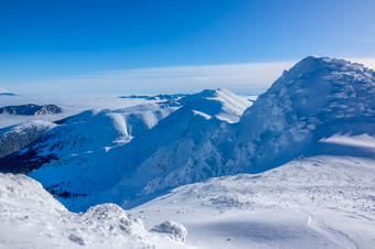 很多雪的<strong>山峰</strong>和山坡上的冬天山阳光明媚的天气和万里无云的蓝色的天空蓝色的天空在雪<strong>山峰</strong>