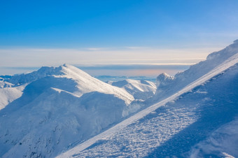 冬天阳光明媚的一天山山峰和蓝色的天空陡峭的滑雪运行下降的前景陡峭的滑雪小道的背景山山峰