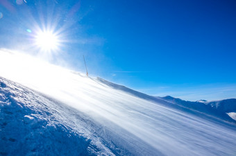 冬天阳光明媚的一天空滑雪坡强大的风提出了很多雪<strong>灰尘</strong>那闪烁的太阳暴风雪阳光明媚的天气空滑雪坡