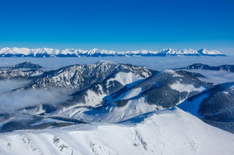 的上衣冬天山和早....雾的山谷阳光明媚的天气和蓝色的天空雪封顶山峰和早....雾