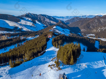 斯洛伐克阳光明媚的冬天一天的明亮滑雪度假胜地蓝色的天空山山峰和滑<strong>雪山</strong>坡上空中视图山山峰和滑<strong>雪山</strong>坡上阳光明媚的天气空中视图