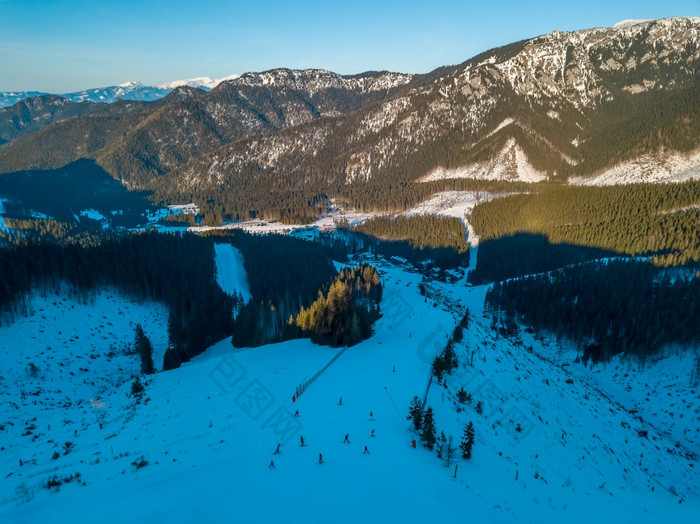 冬天斯洛伐克阳光明媚的一天的明亮滑雪度假胜地蓝色的天空山山峰和滑雪山坡上空中视图冬天山山峰和滑雪山坡上阳光明媚的天气空中视图