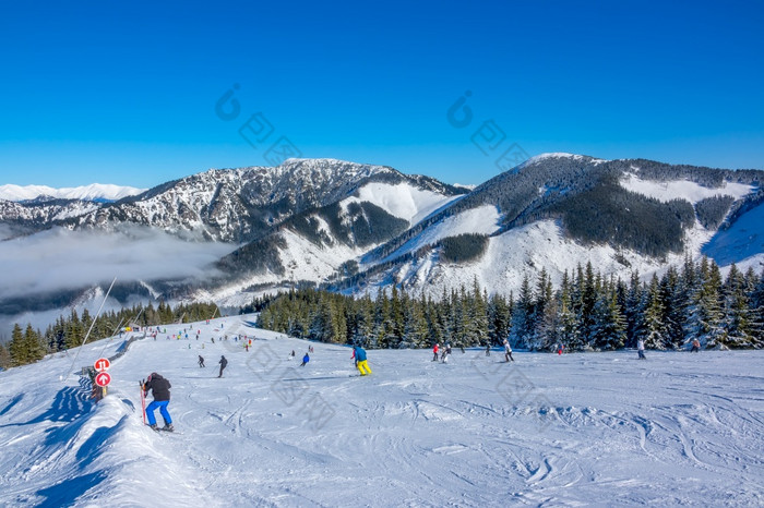 冬天山宽和温柔的滑雪坡阳光明媚的天气很多滑雪者光雾的谷很多滑雪者宽和温柔的滑雪坡阳光明媚的天气