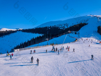 斯洛伐克冬天明亮阳光明媚的一天滑雪山坡上的树木繁茂的山太阳照明亮和蓝色的天空空中视图滑雪者的滑雪坡阳光明媚的冬天一天空中视图