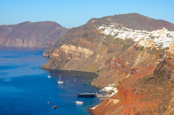 希腊圣托里尼岛火山口阳光明媚的一天aio村的坡岩石海岸几个航行和电动机游艇白色房子aio阳光明媚的一天和几个游艇停附近圣托里尼岛