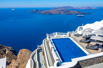 希腊锡拉岛圣托里尼岛酒店的高银行aio池和太阳便鞋为放松阳光明媚的天气海景酒店池高银行和海景与船