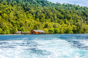 热带岛印尼木码头和小屋的海岸水泡沫后面的斯特恩的游艇水泡沫倒车当航行从热带岛与小屋